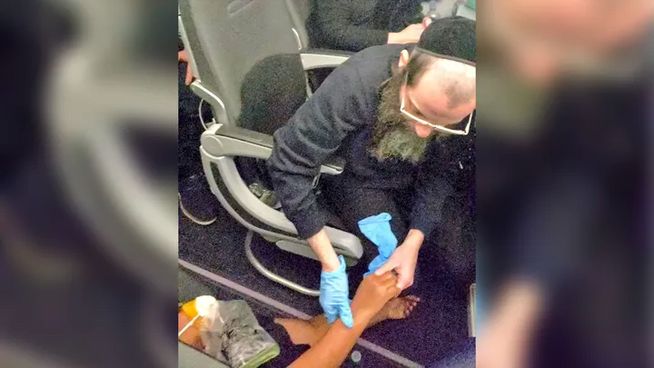 A man is seen helping a woman after she passed out during a JetBlue flight from New York to Florida on Thursday, January 26, 2023. (E.S./Simon Gifter (@nycphotog))